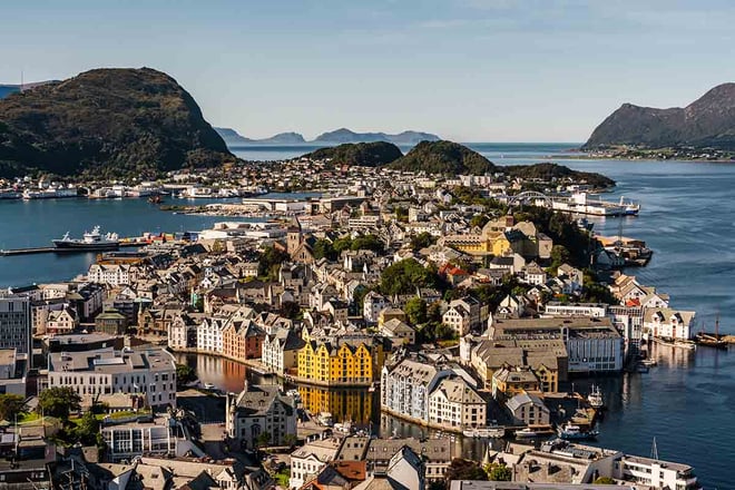 Oversiktsbilde av en middels stor by som ligger på øyer ut mot havgapet. Noen av husene i midten av bildet er gule og røde, de fleste andre er grå og hvite