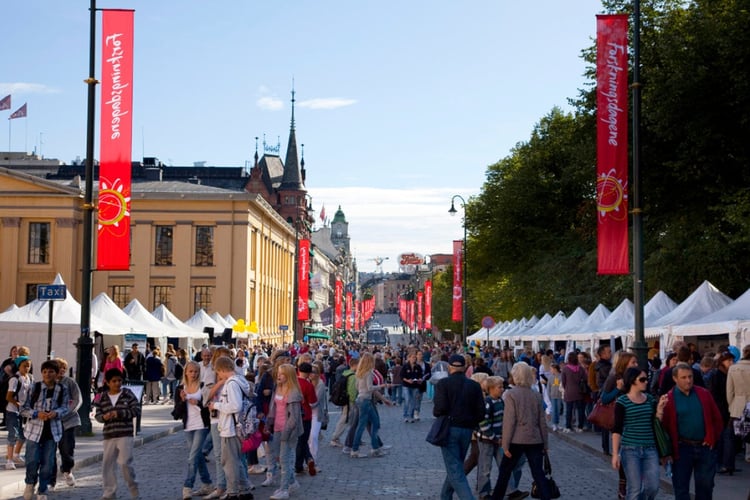 Folkemengde blant telt og boder på forskningstorg i Karl Johans gate, Oslo. Røde Forskningsdagene-bannere henger fra alle gatelykter langs veien.