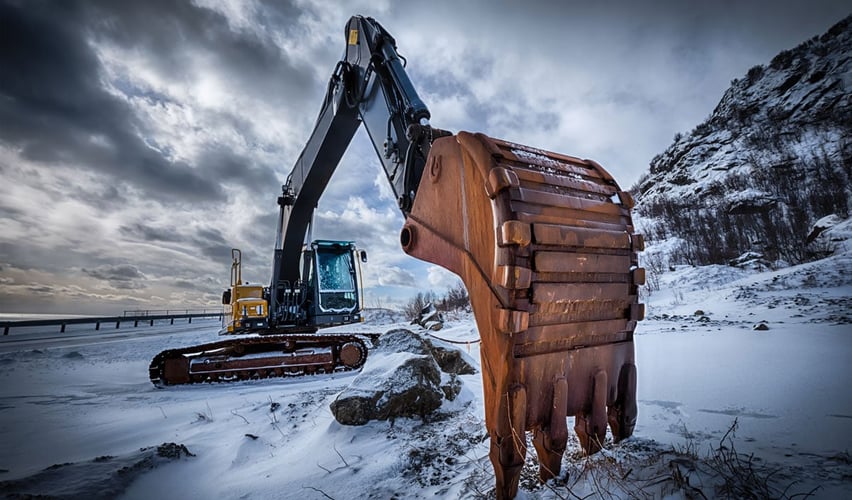 Gravemaskin på snødekt anleggsplass